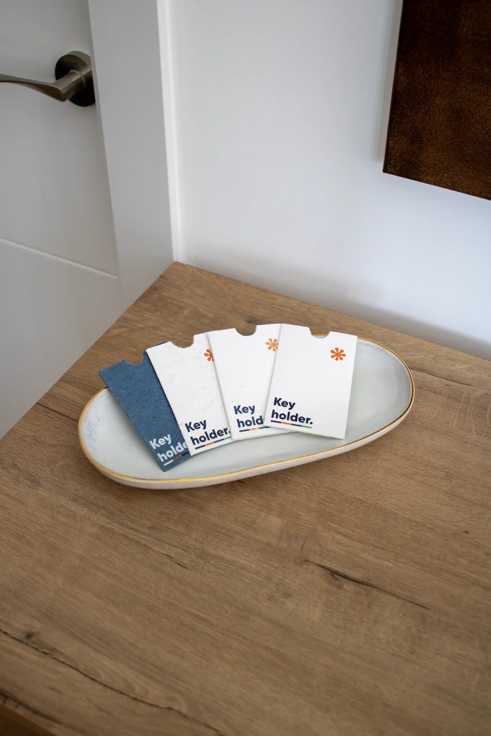Porta llaves hotel sobre SAK 4 porta llaves de hotel personalizados colocados en una bandeja sobre una mesa de madera
