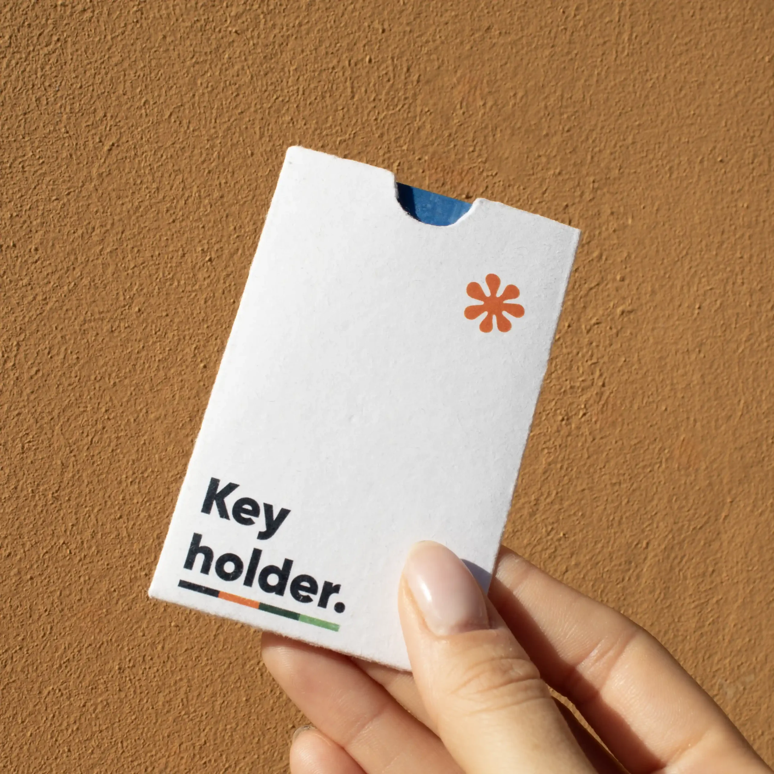 Mano mostrando un porta llaves de hotel en papel ecológico blanco personalizado con la palabra key holder en azul