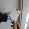 Mano mostrando un porta llaves de hotel en papel ecológico blanco personalizado con la palabra key holder en azul antes de abrir la puerta