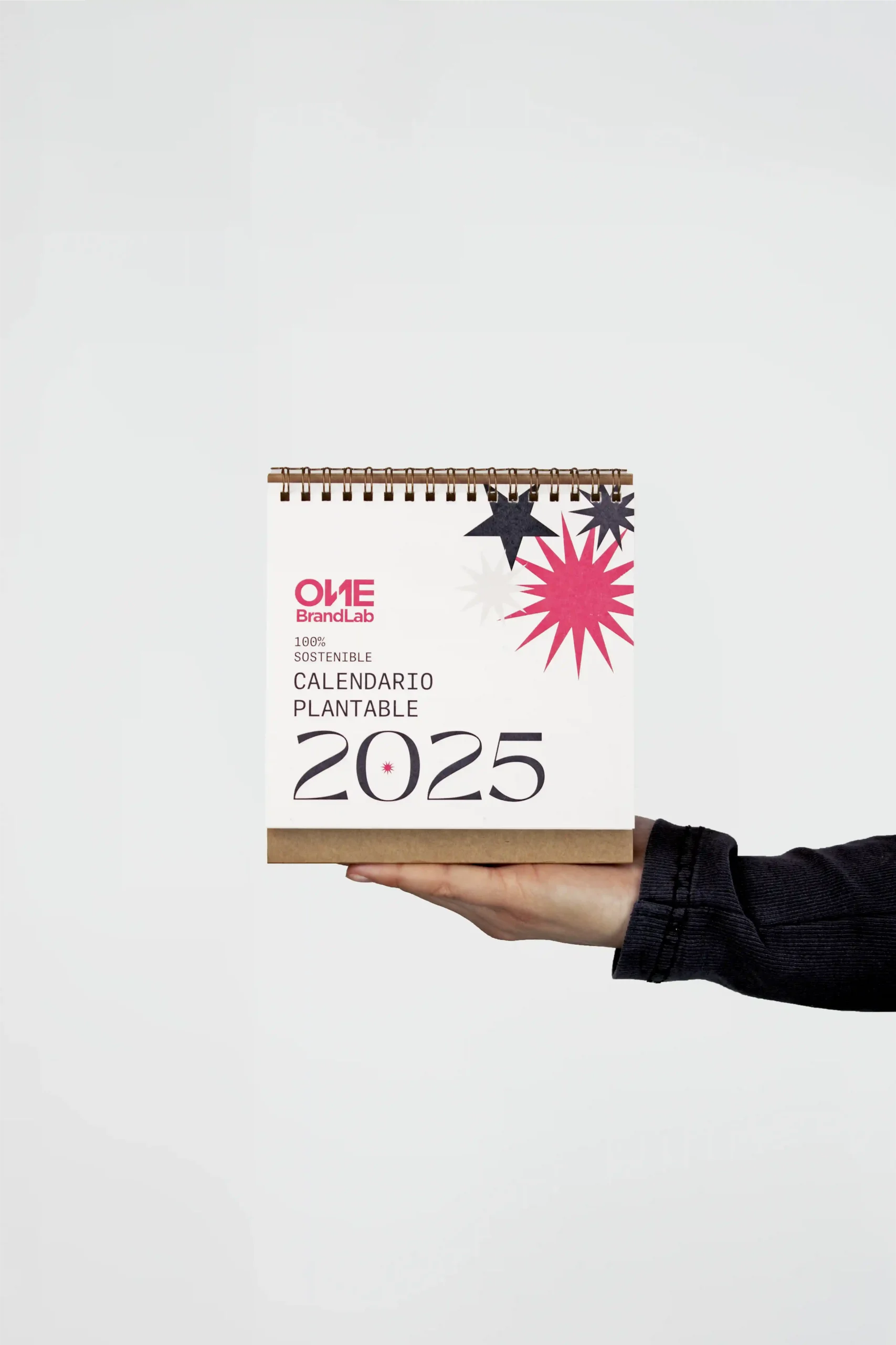 Mano sujetando un calendario plantable 2025 personalizado para la agencia One Brand Lab