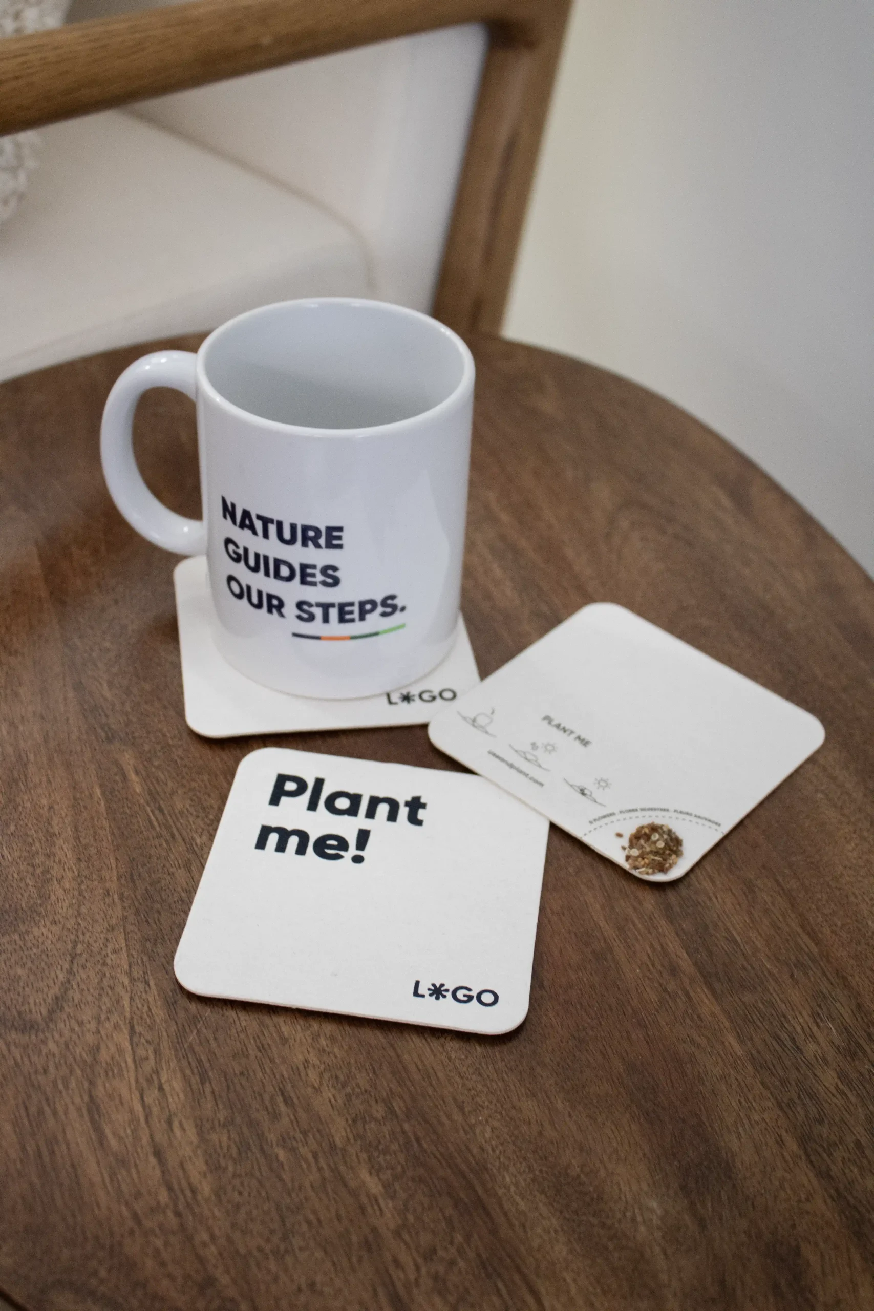 Sous-verres en carton MOK + Mug DALIA 3 posavasos de cartón personalizados junto a una taza blanca sobre una mesa de madera