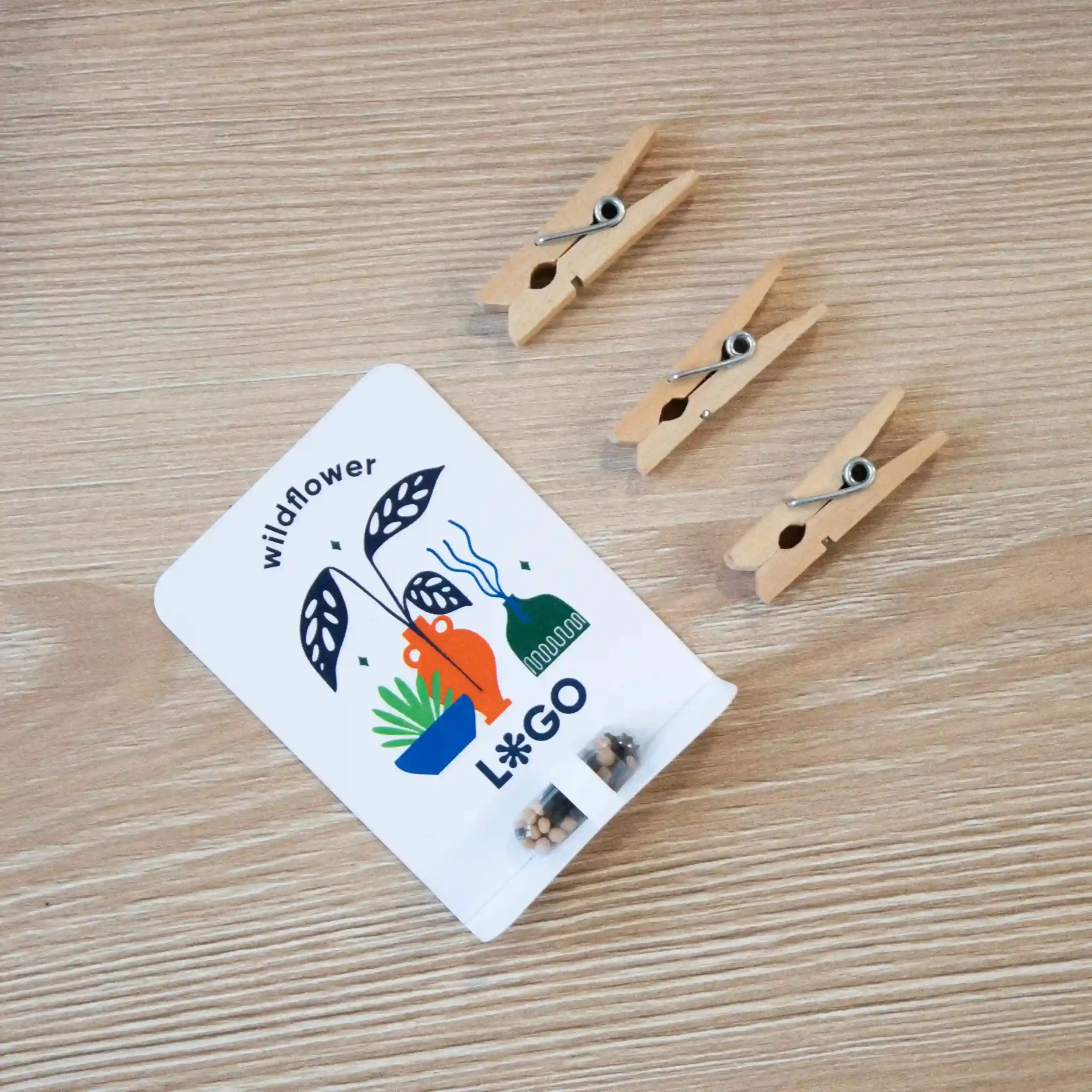 Cápsula biodegradable con semillas en su interior con packaging de cartón blanco personalizado sobre una mesa de madera