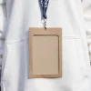 Funda de acreditación kraft y lanyard de rPET azul personalizado colgado del cuello de una persona con jersey blanco