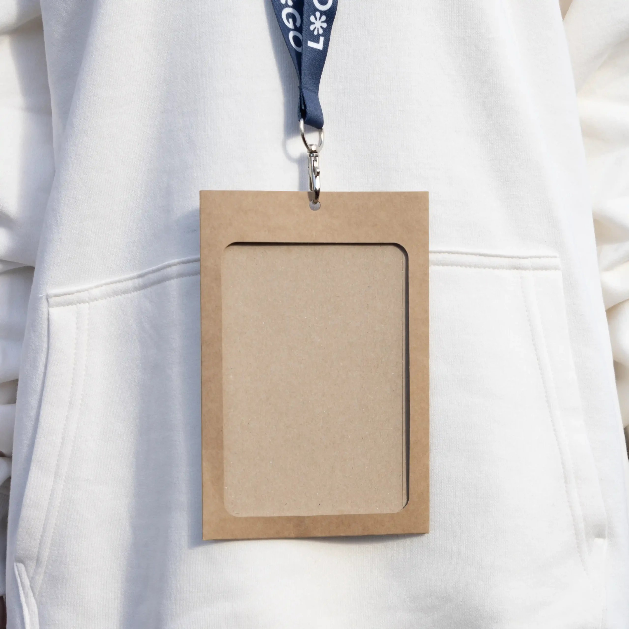 Kit B: Funda KASE Kraft 0/0 + Lanyard COLLIN Funda de acreditación kraft y lanyard de rPET azul personalizado colgado del cuello de una persona con jersey blanco