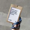Mano sujetando una acreditación personalizada con funda kraft y lanyard de rPET azul personalizado con el texto 'logo' en blanco