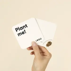 Mano mostrando 2 posavasos de cartón personalizados con semillas pegadas en una esquina