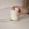 Una mano dejando una taza blanca sobre un posavasos de cartón personalizado