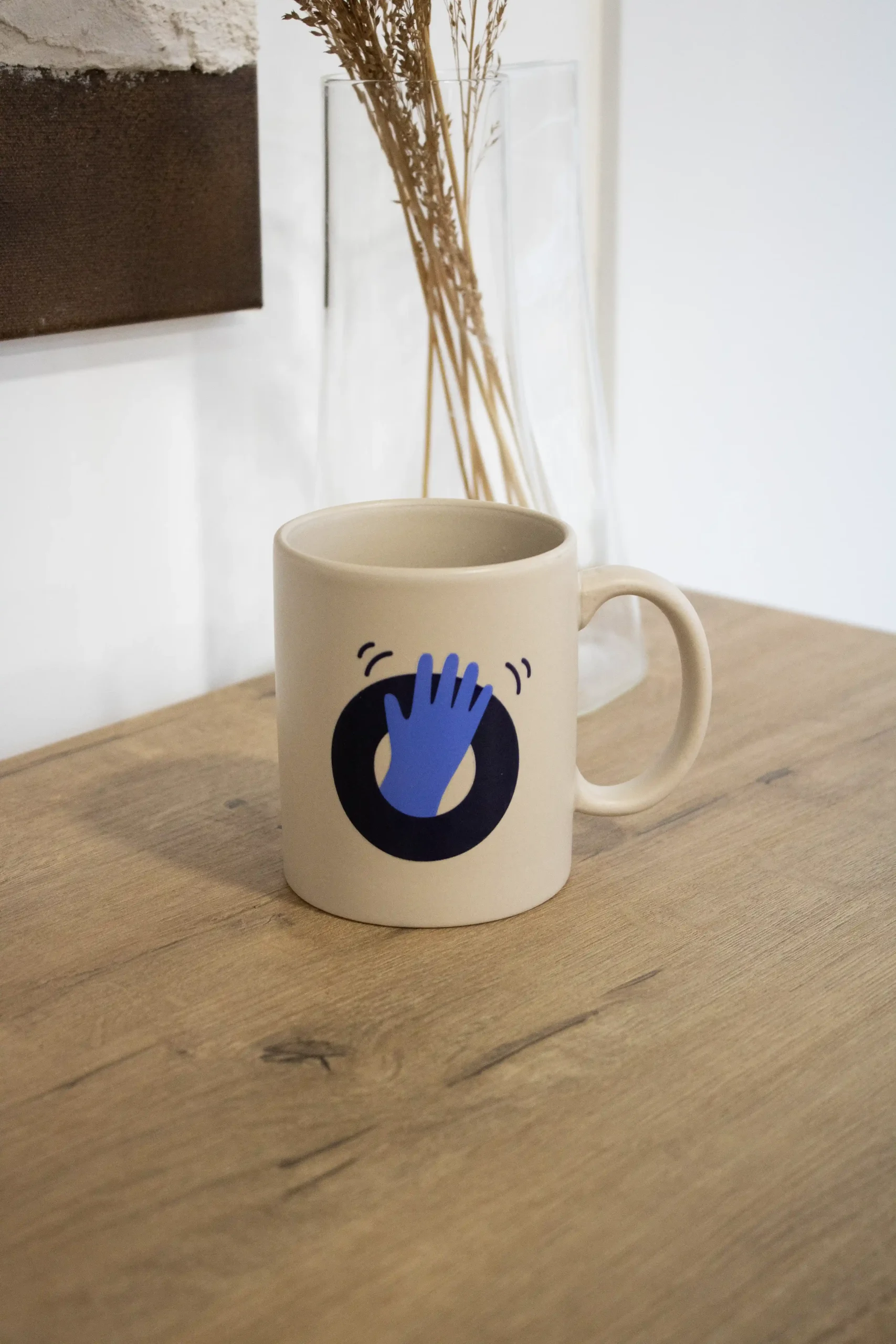 Pack 'Welcome to the team': VANILLE Taza de cerámica beige personalizada con una ilustración en color azul sobre una superficie de madera