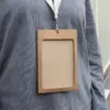 Funda de acreditación de cartón kraft marrón colgada de un lanyard de algodón blanco colocado en el cuello de una persona