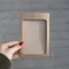 Mano mostrando una funda de acreditación en cartón kraft marrón