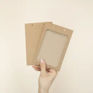 Mano mostrando dos fundas de acreditación en cartón kraft marrón