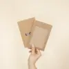 Mano mostrando dos fundas de acreditación en cartón kraft marrón