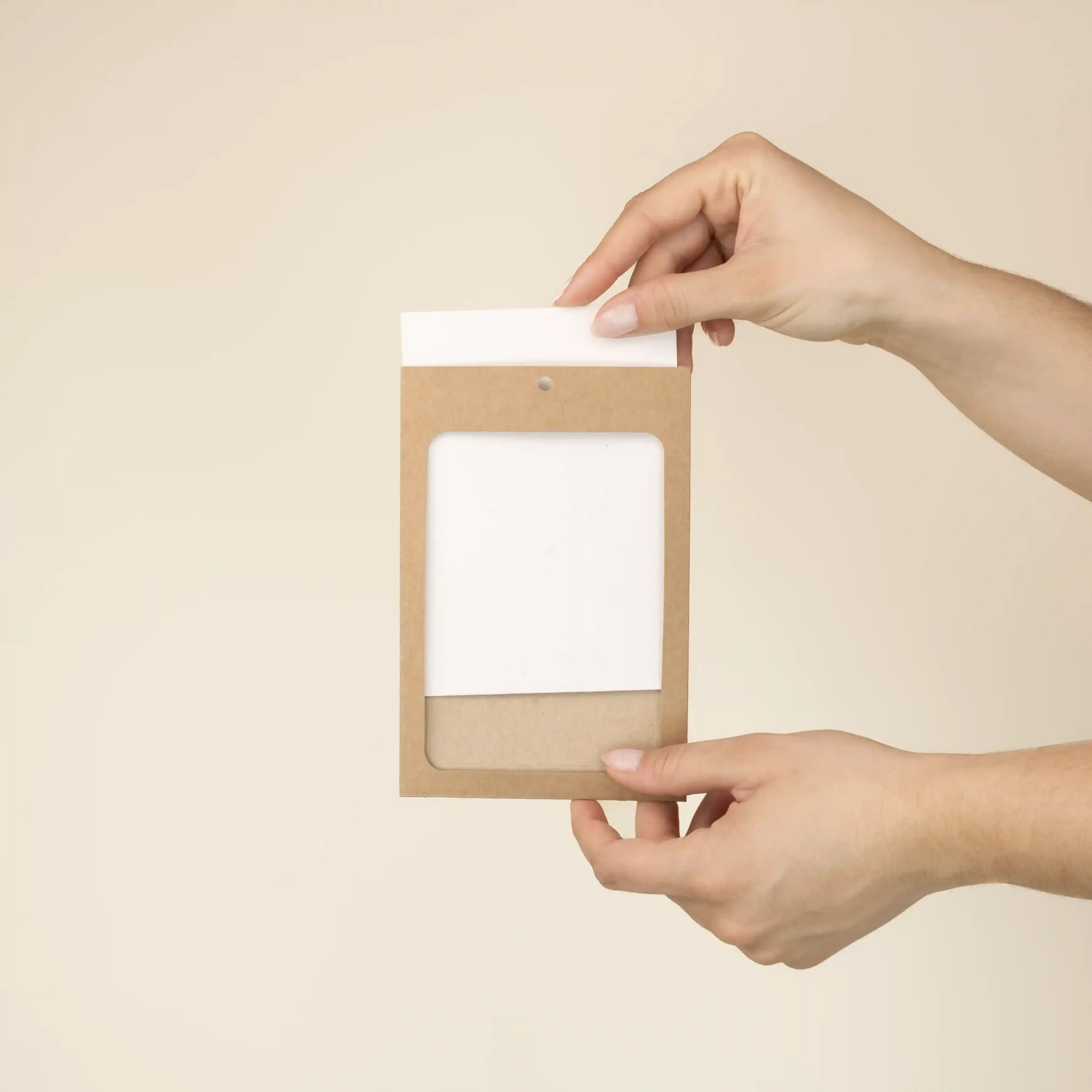 Funda acreditación KASE 4/0, A6 (13x9 cm) Dos manos metiendo una acreditación de papel blanco en una funda de cartón kraft marrón