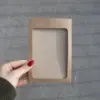 Mano mostrando una funda de acreditación en cartón kraft marrón