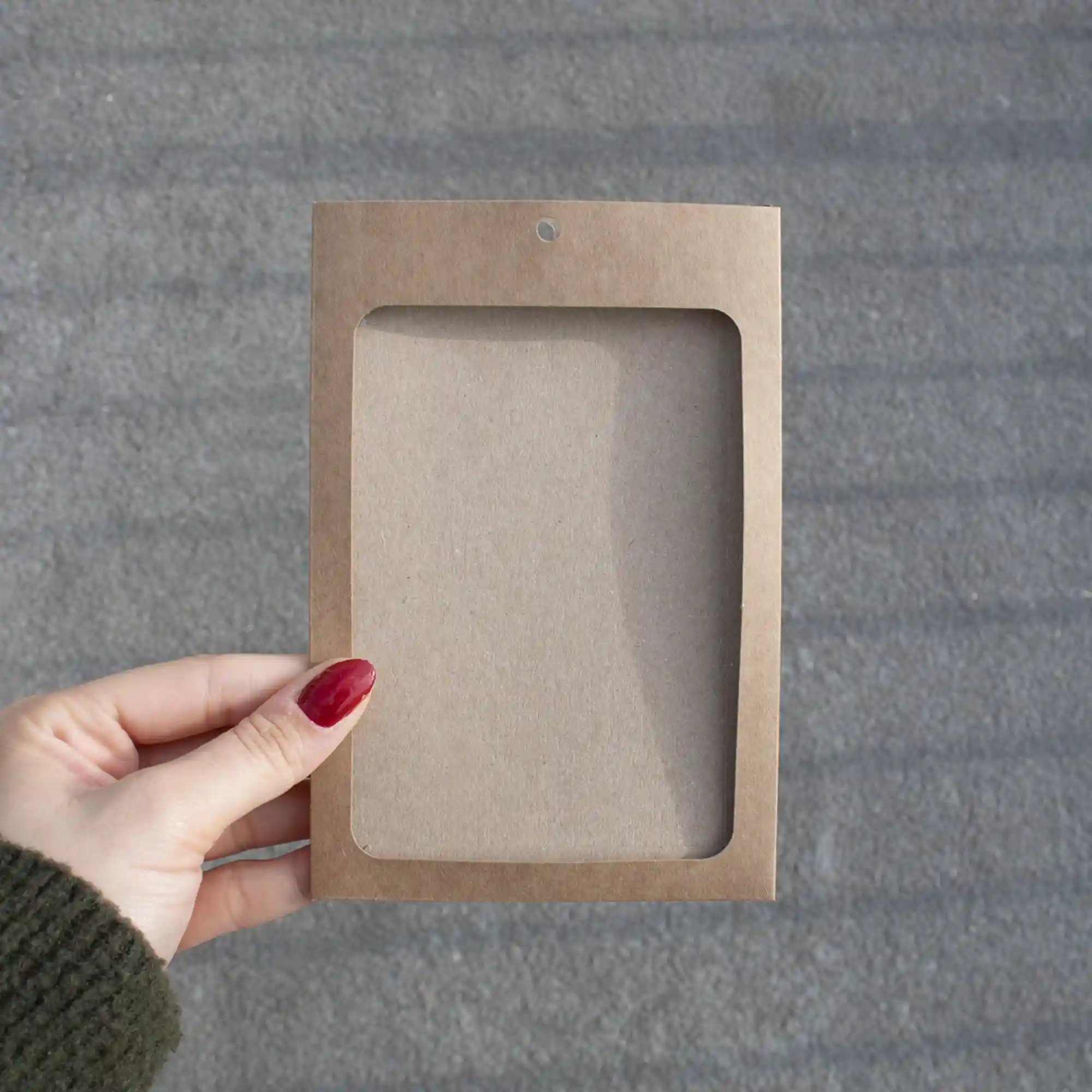 Funda acreditación KASE 4/0, A6 (13x9 cm) Mano mostrando una funda de acreditación en cartón kraft marrón