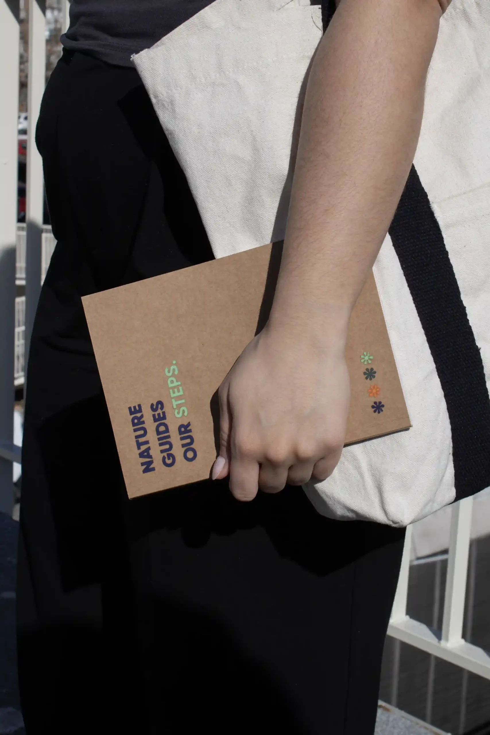 Carnet écologique KLAAS Chica llevando en la mano un cuaderno ecológico kraft personalizado con el texto 'Nature guides our steps'