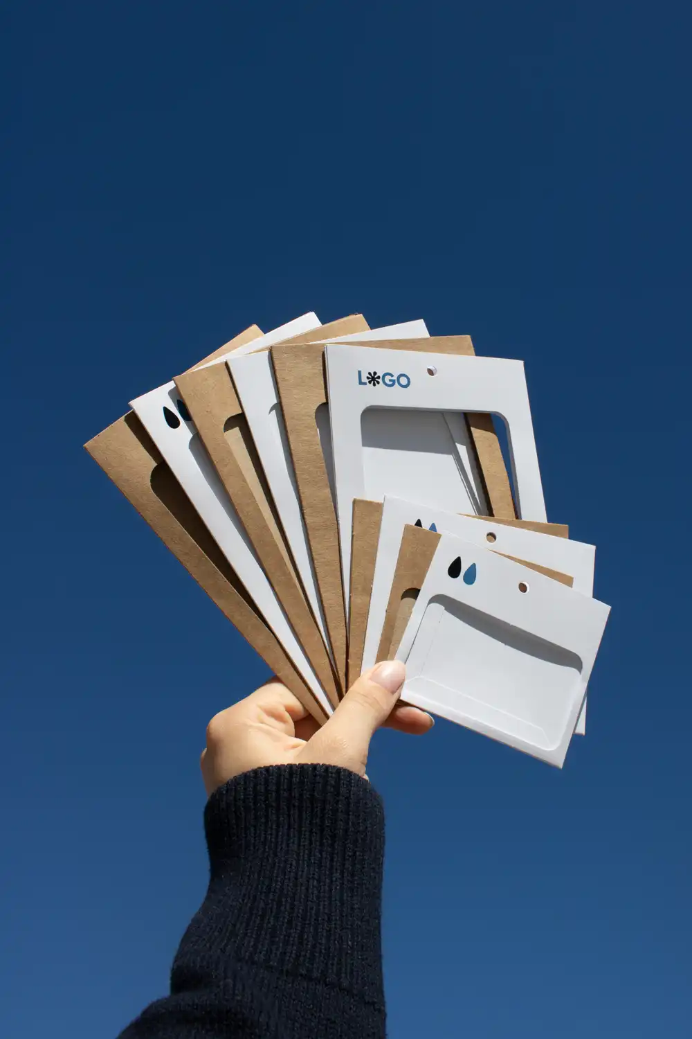 Porte-badge KASE 4/4 Mano mostrando un conjunto de fundas de acreditación personalizadas en forma de abanico con el cielo de fondo