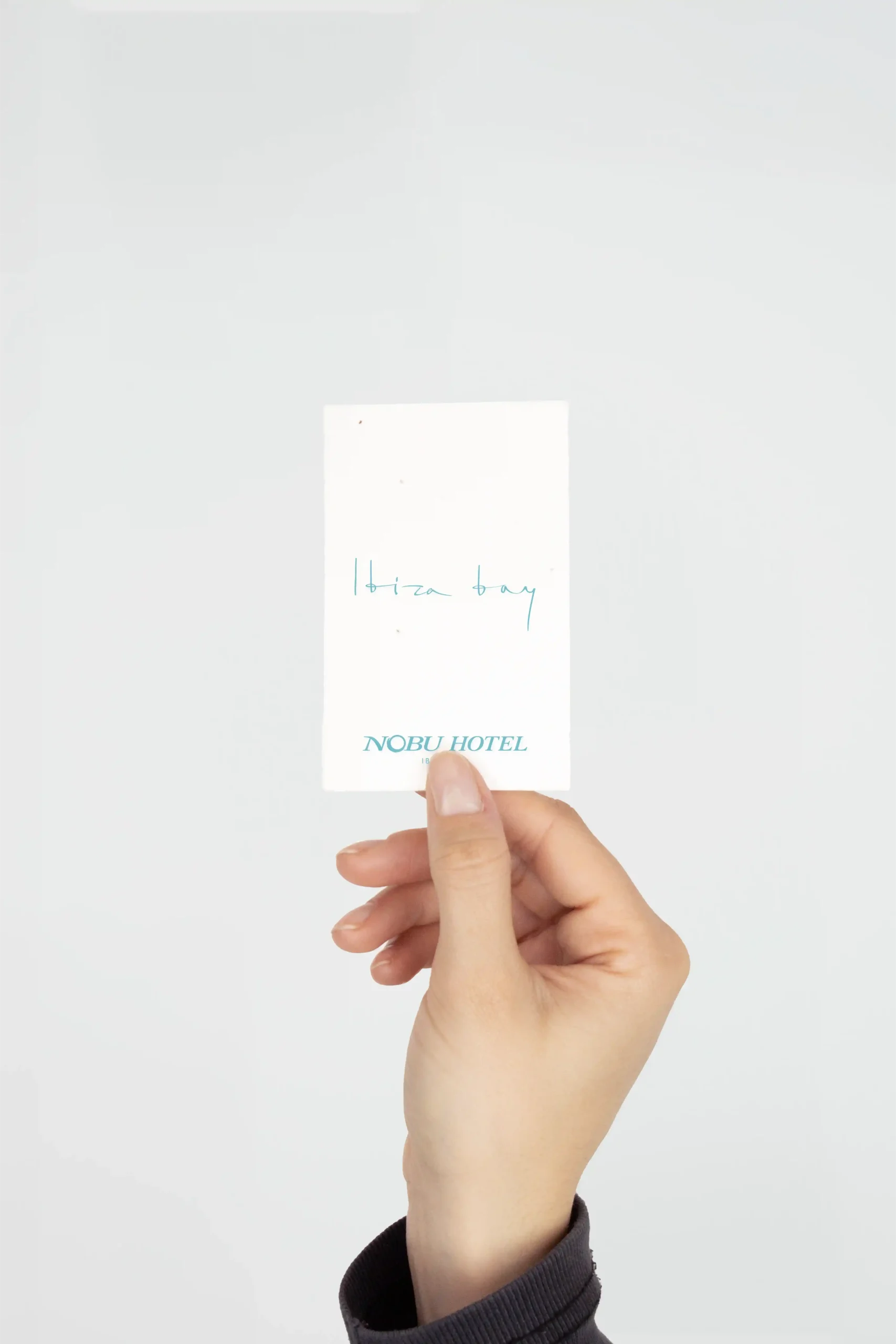 Mano sujetando un porta llaves de hotel de papel plantable personalizado para NOBU HOTEL
