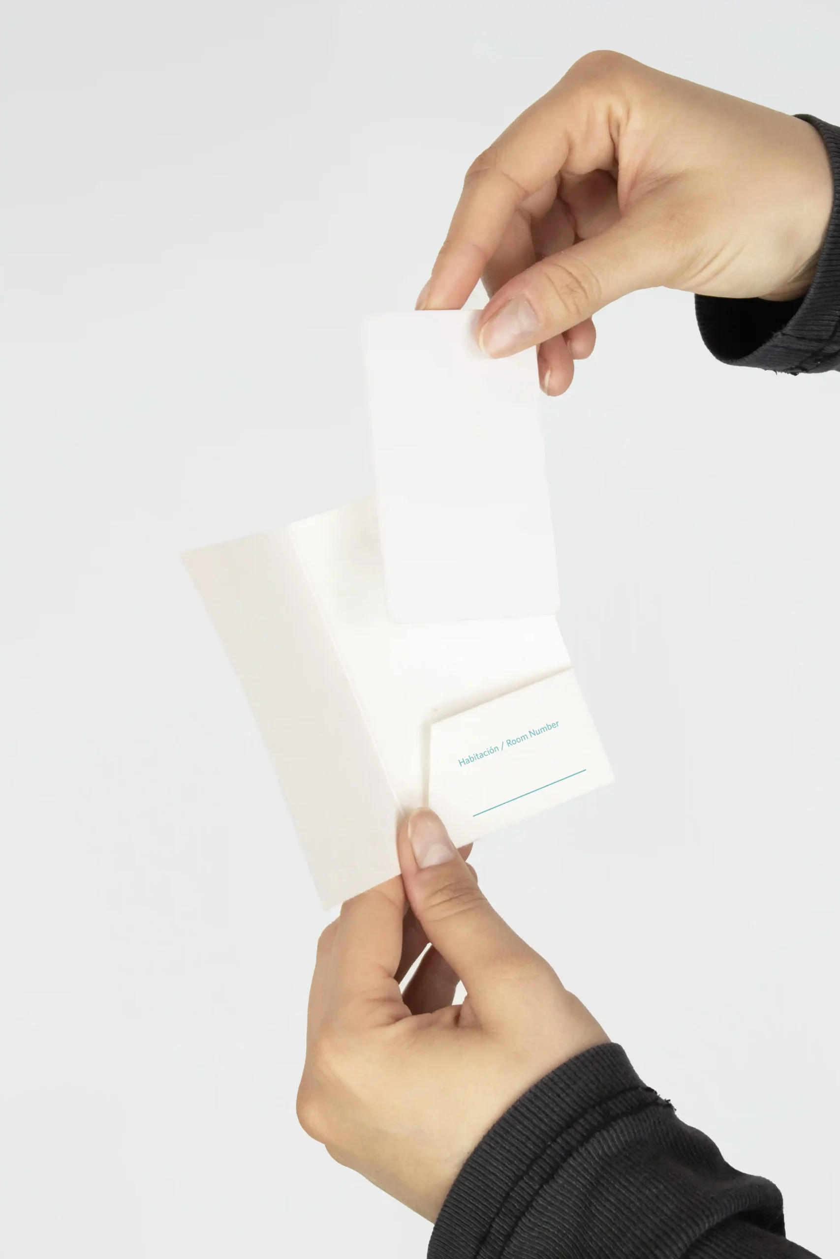 Dos manos sujetando un porta llaves de hotel de papel plantable personalizado para NOBU HOTEL