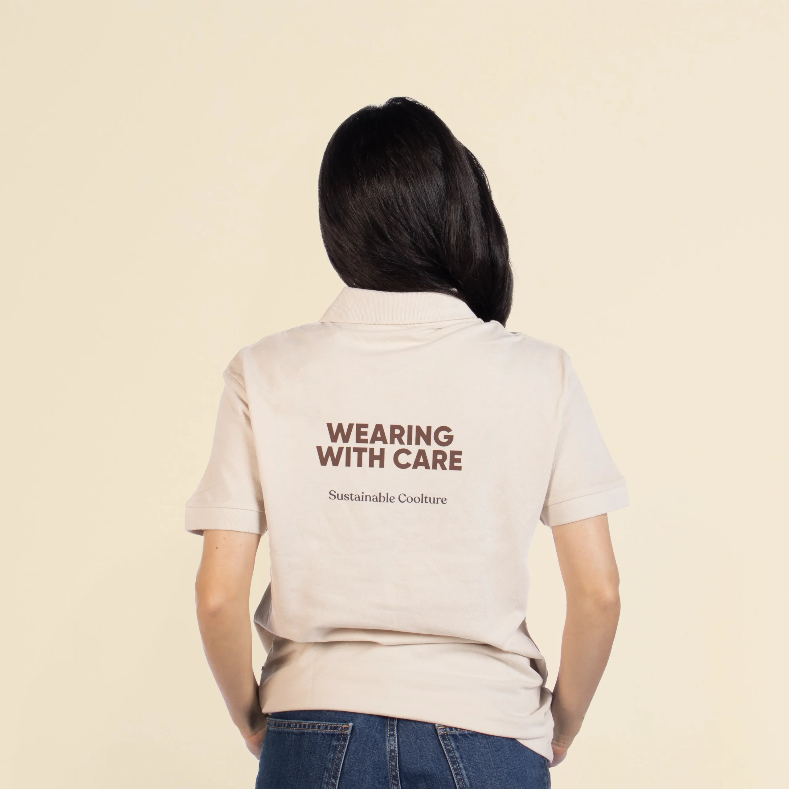 Polo de algodón POL Beige Chica de espaldas llevando con un polo beige personalizado con el texto en marrón "Wearing with care"