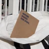 Cuaderno plantable kraft personalizado con el texto 'Nature guides our steps' dentro de una bolsa de algodón blanca