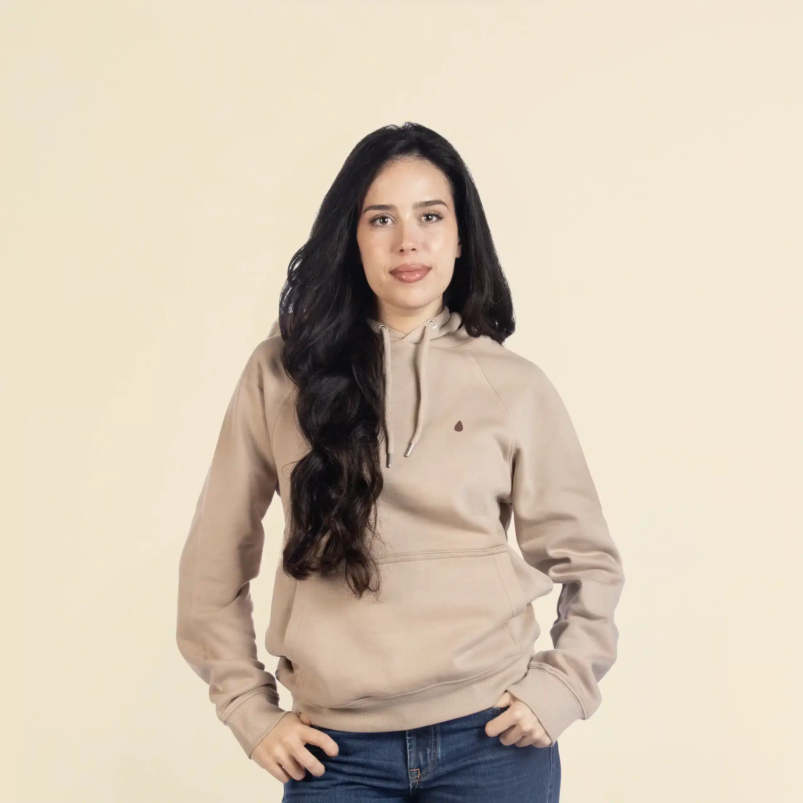 Sudadera con capucha HUVA Beige Chica morena de frente llevando jeans y una sudadera con capucha beige personalizada