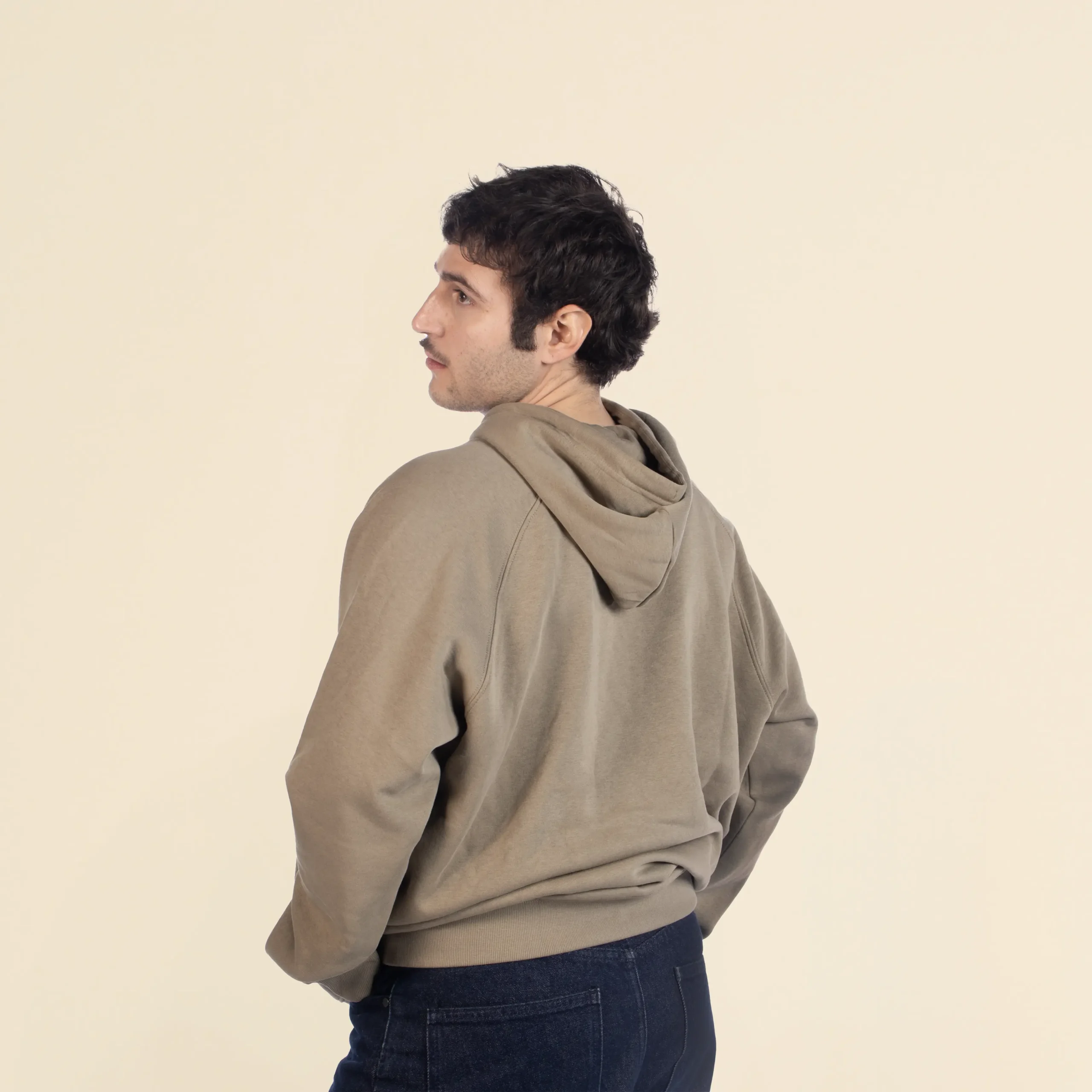 Sudadera con capucha HUVA Verde Chico moreno de espaldas llevando jeans y una sudadera verde con capucha personalizada