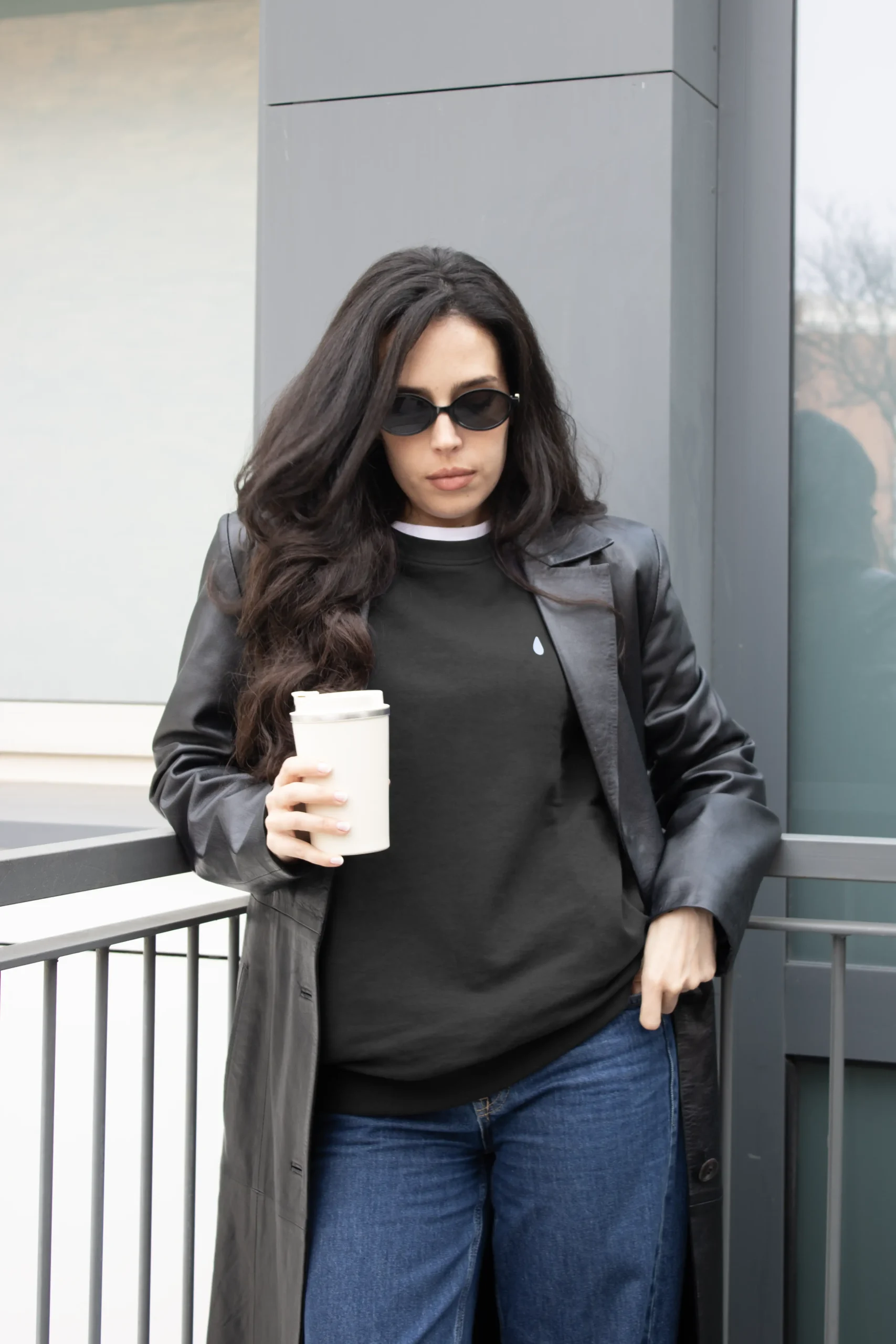 Sweat sans capuche SEDRA Noir Chica morena con gafas de sol y un termo en la mano, llevando jeans y una sudadera negra personalizada