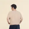 Chico moreno de espaldas llevando jeans y una camiseta de algodón beige