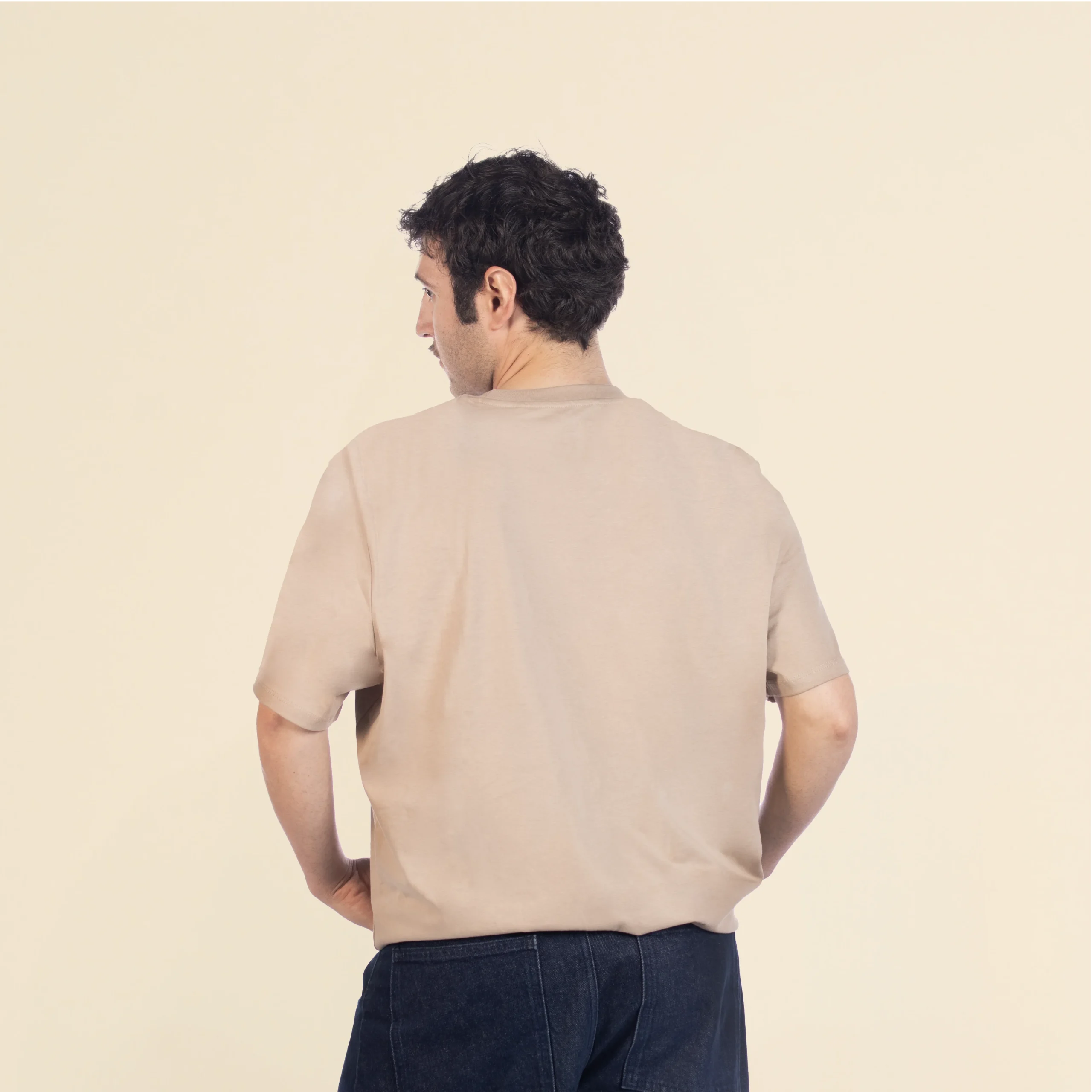 Camiseta de algodón TESSA Beige Chico moreno de espaldas llevando jeans y una camiseta de algodón beige