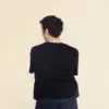 Chico moreno de espaldas llevando jeans y una camiseta de algodón negra