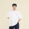 Chico moreno de frente llevando jeans y una camiseta oversize blanca personalizada