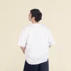 Chico moreno de espaldas llevando jeans y una camiseta oversize blanca