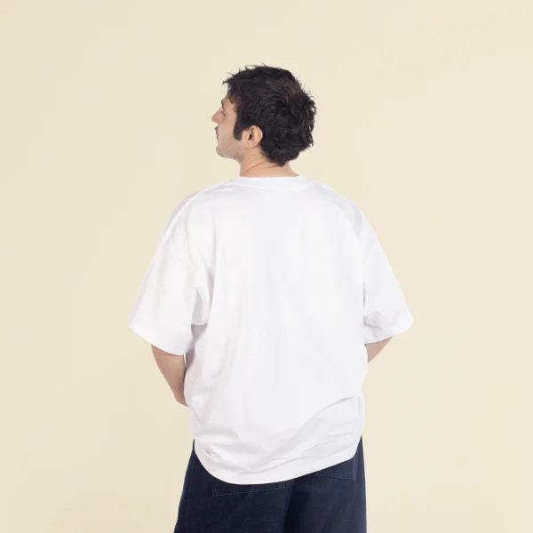 Chico moreno de espaldas llevando jeans y una camiseta oversize blanca
