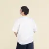 Chico moreno de espaldas llevando jeans y una camiseta oversize blanca