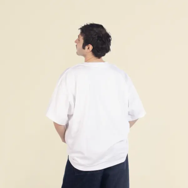 Chico moreno de espaldas llevando jeans y una camiseta oversize blanca