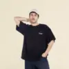Chico moreno de frente llevando jeans y una camiseta oversize negra personalizada