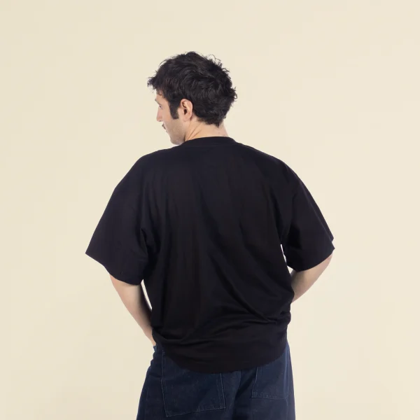 Chico moreno de espaldas llevando jeans y una camiseta oversize negra
