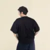 Chico moreno de espaldas llevando jeans y una camiseta oversize negra