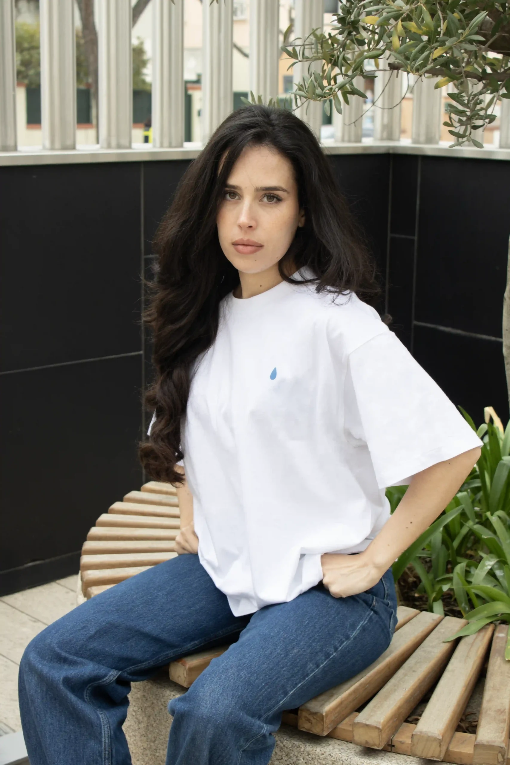Camiseta oversize VEGA Blanca Chica morena sentada de frente llevando jeans y una camiseta oversize blanca personalizada