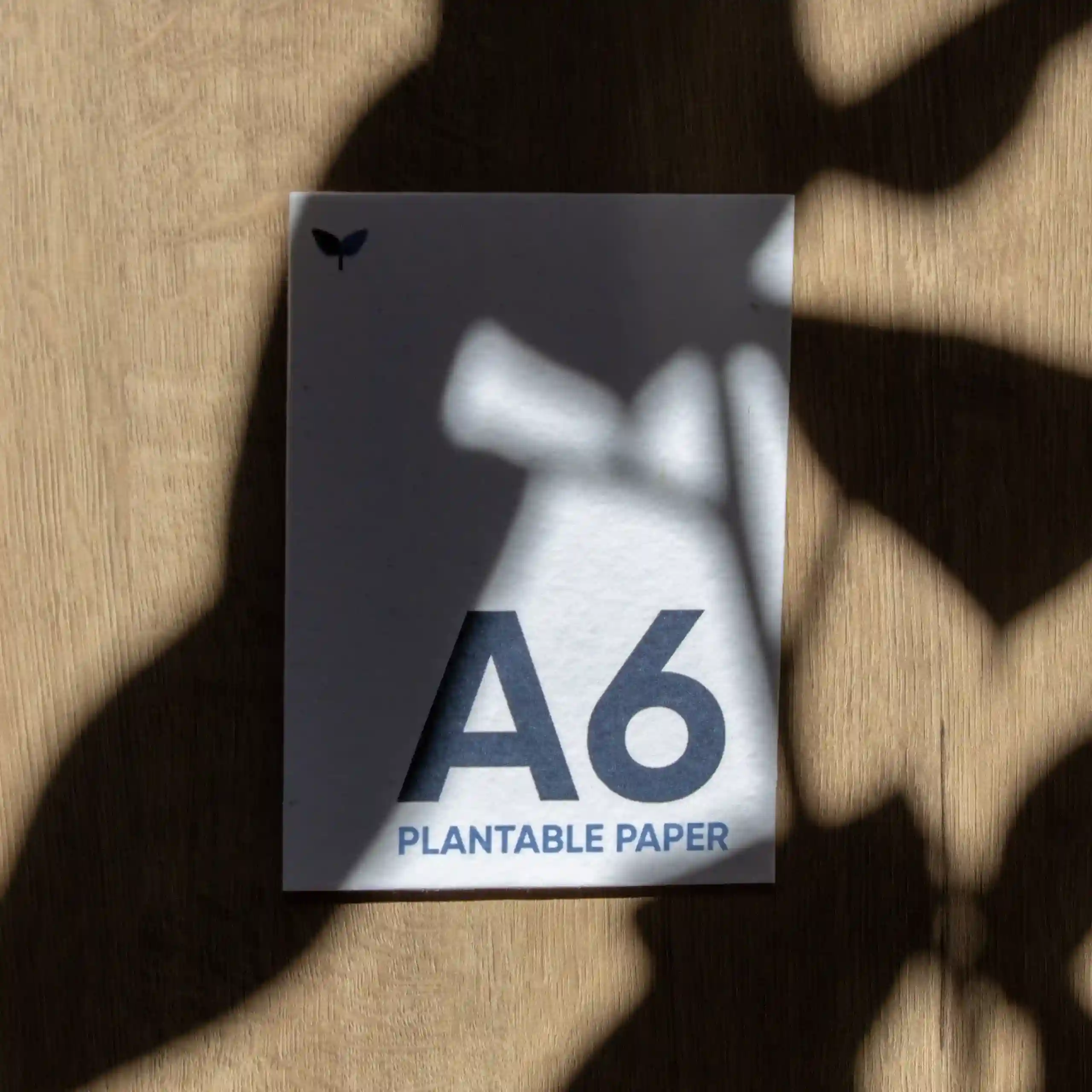 A6 plantable card Tarjeta A6 impresa en papel plantable sobre una superficie de madera con sombras