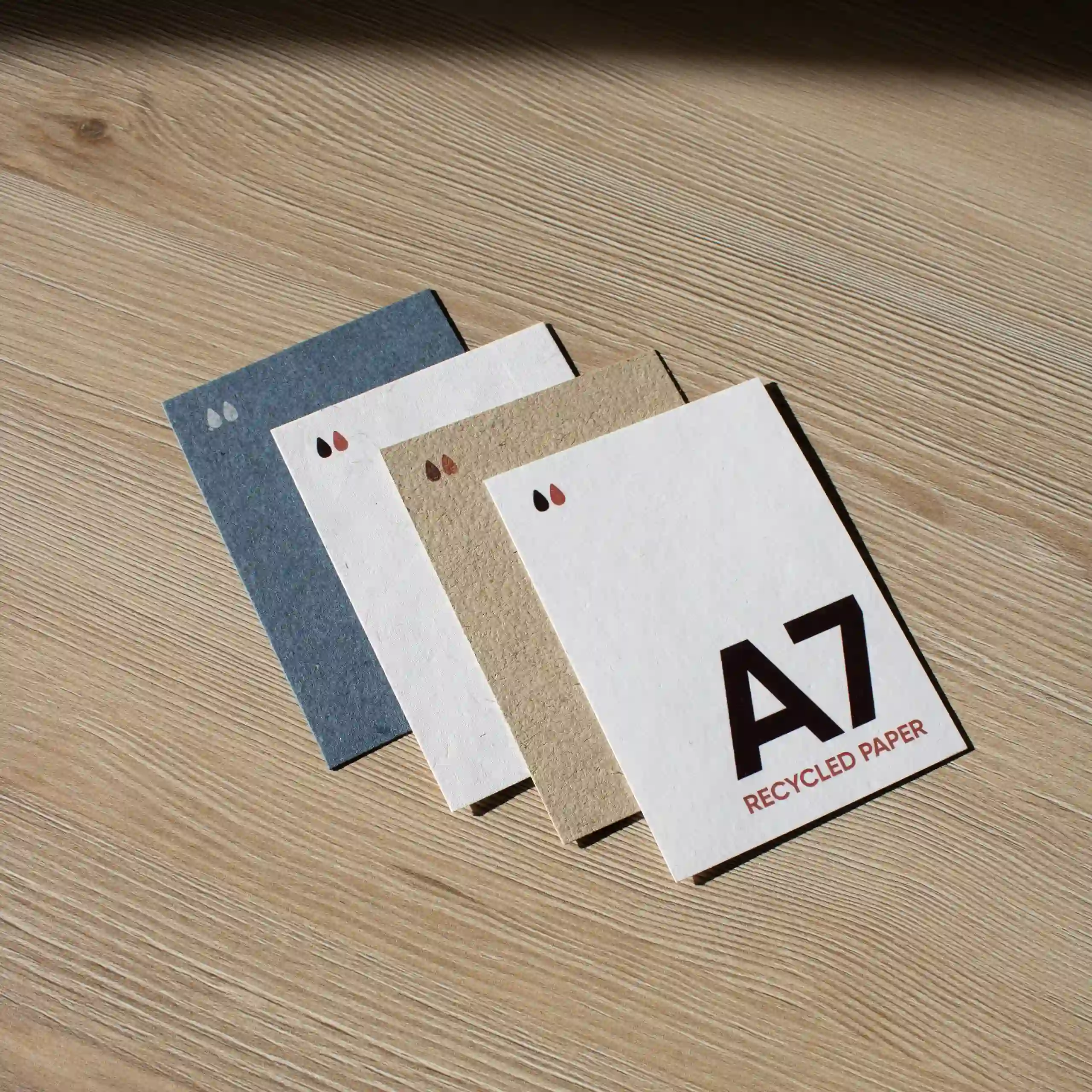 Carte A7 en papier écologique Cuatro tarjetas A7 impresas en papeles ecológicos sobre una superficie de madera
