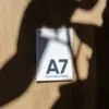 Tarjeta A7 impresa en papel plantable sobre una superficie de madera con sombras