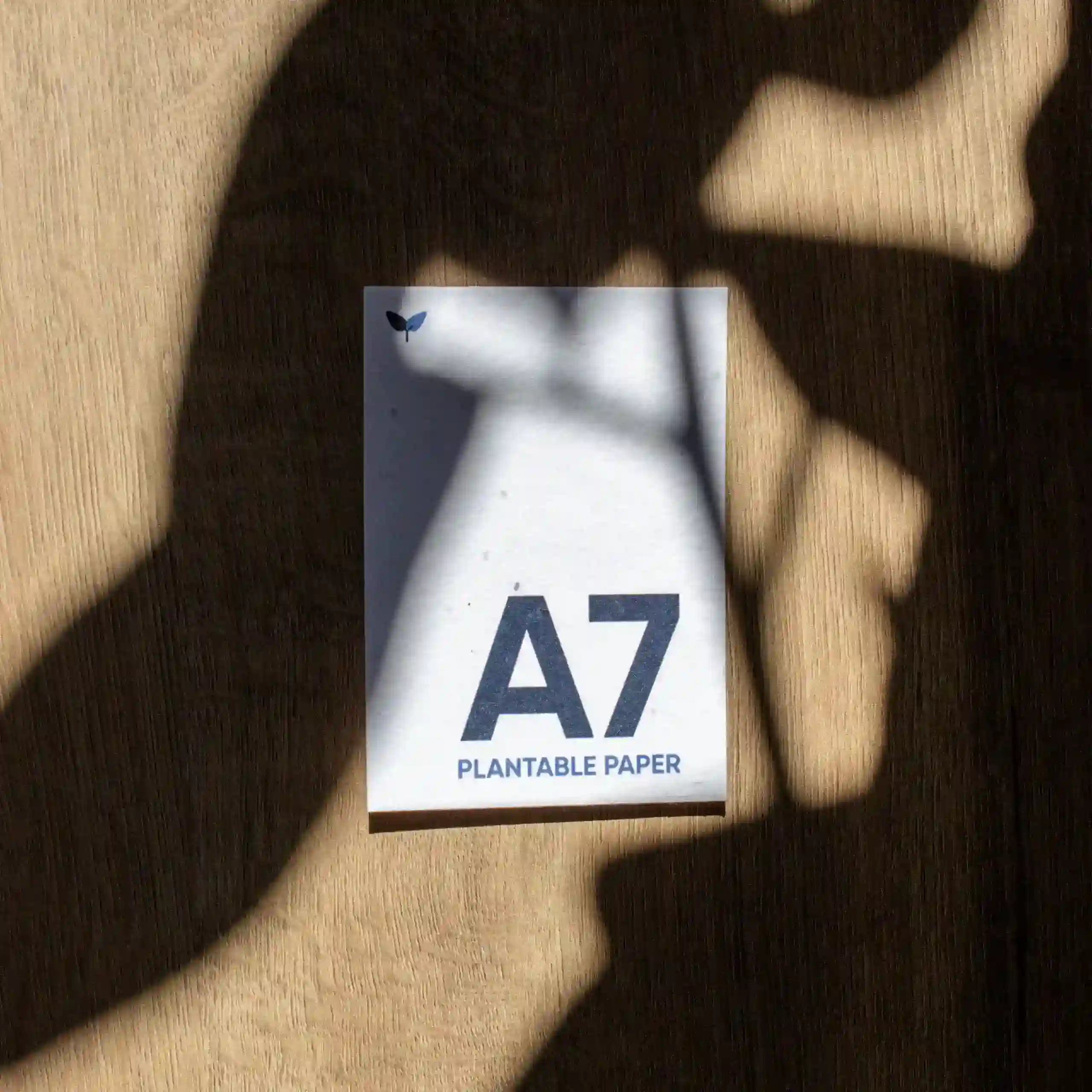 Carte A7 plantable Tarjeta A7 impresa en papel plantable sobre una superficie de madera con sombras