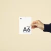 Mano mostrando una acreditación A6 impresa en papel plantable