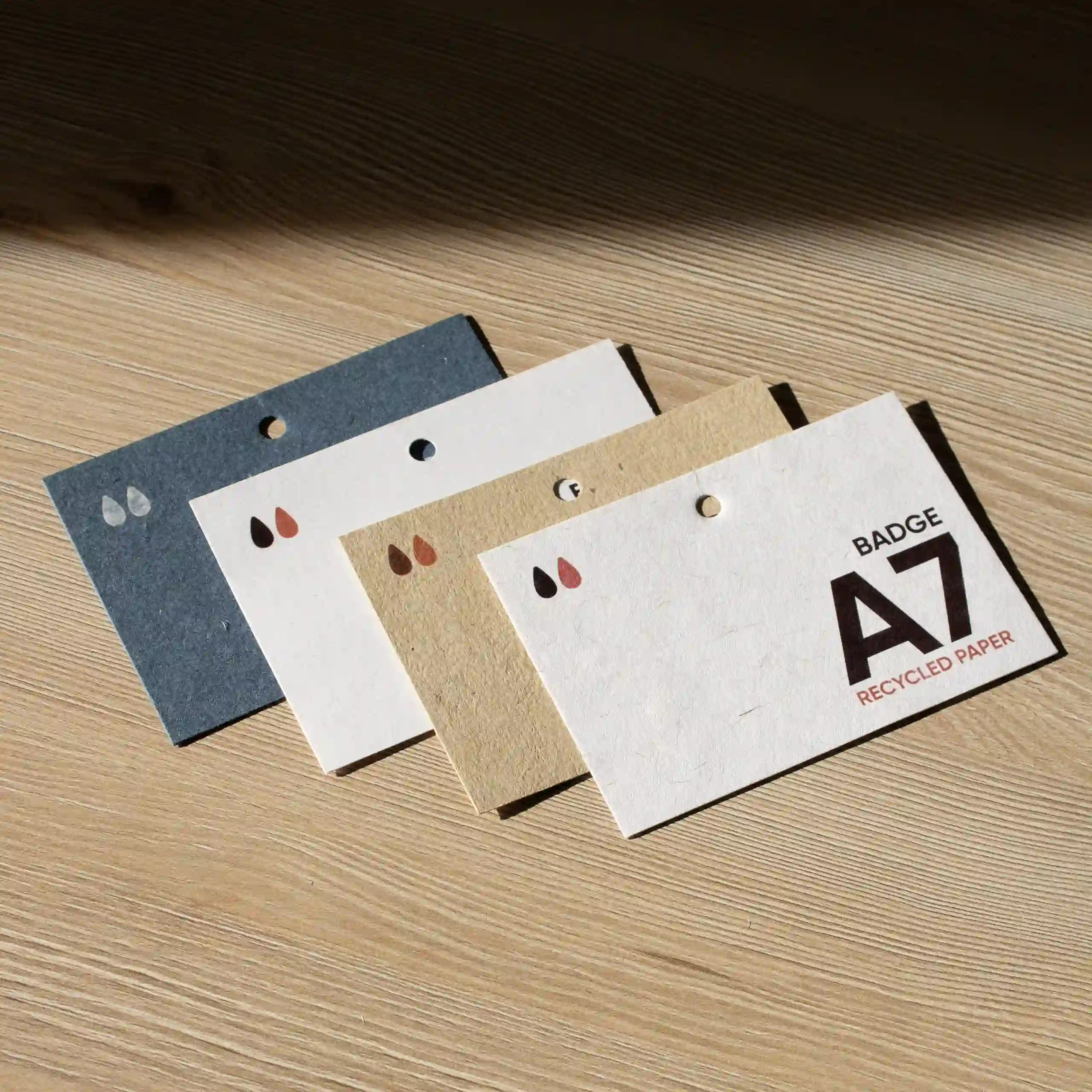 Badge A7 en papier écologique Cuatro acreditaciones A7 impresas en papeles ecológicos sobre superficie de madera