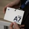 Manos sujetando una acreditación A7 impresa en papel plantable colgada de un lanyard