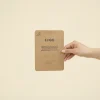 mano sujetando un tarjetón A6 impreso en papel kraft