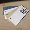 Cuatro tarjetas DL impresas en papel ecológico sobre una superficie de madera