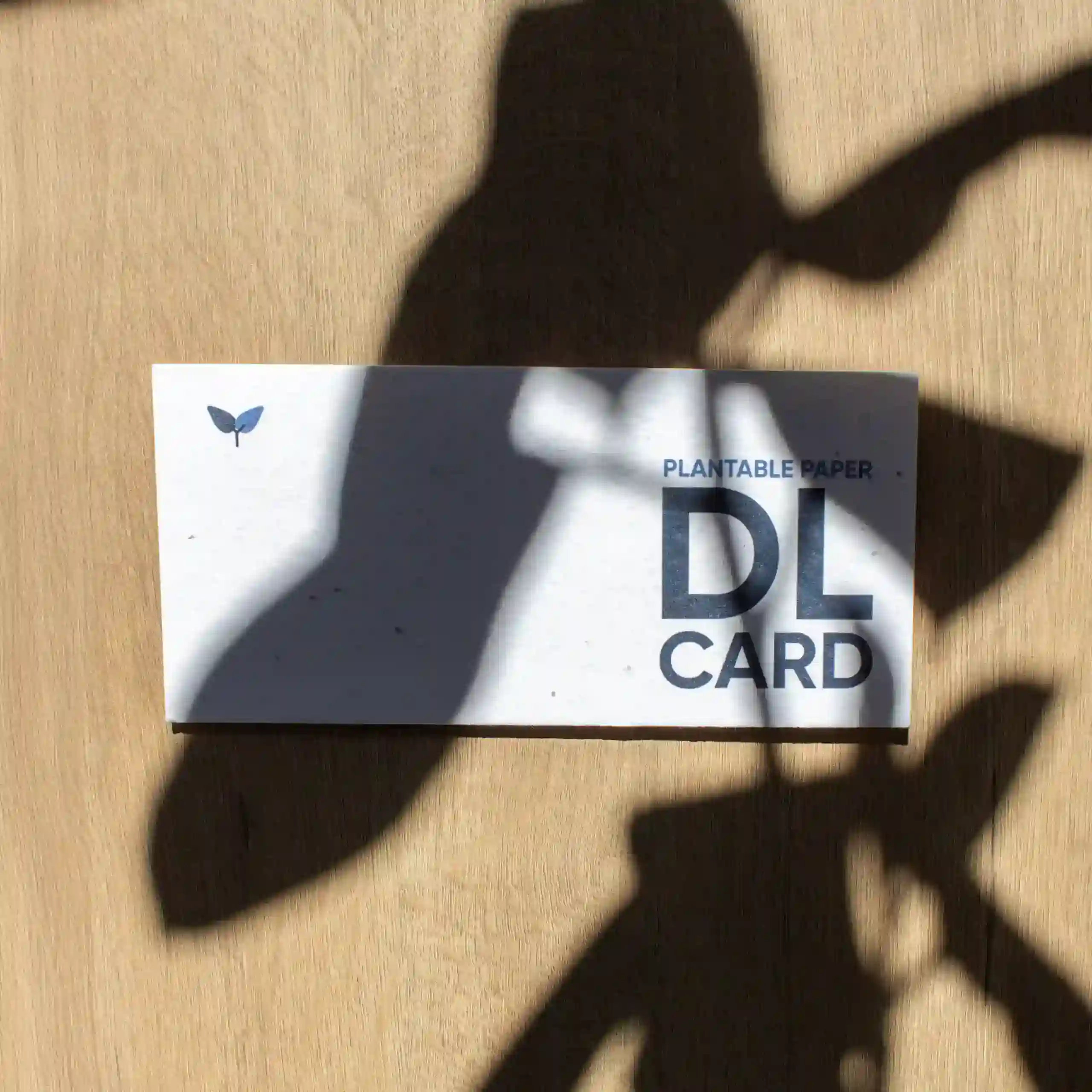 Tarjetón americano DL plantable Tarjeta DL impresa en papel plantable sobre una superficie de madera con sombras